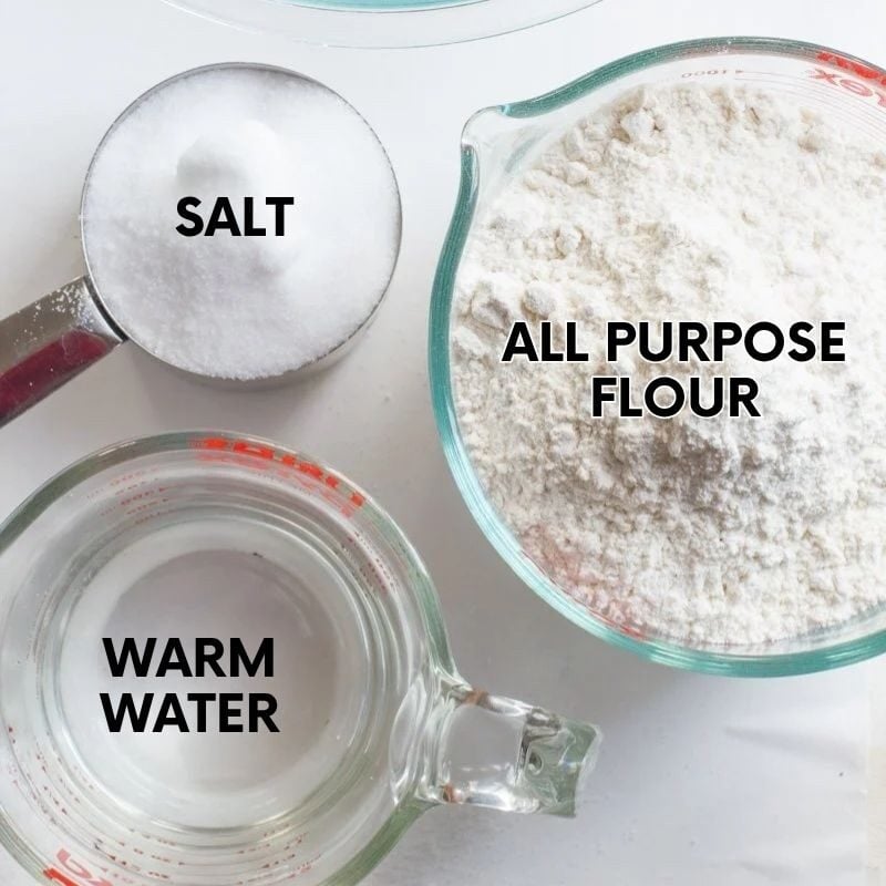 The ingredients for the salt dough recipe—flour, salt, and water—lie flay on a white countertop.
