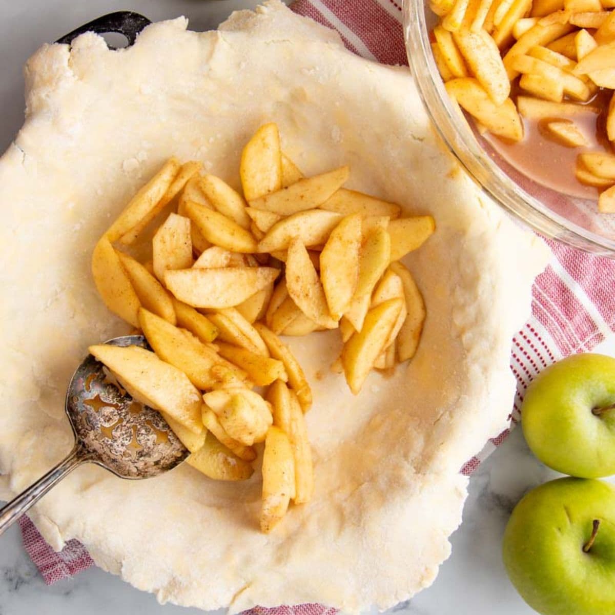A metal spoon scoops filling into a pie crust