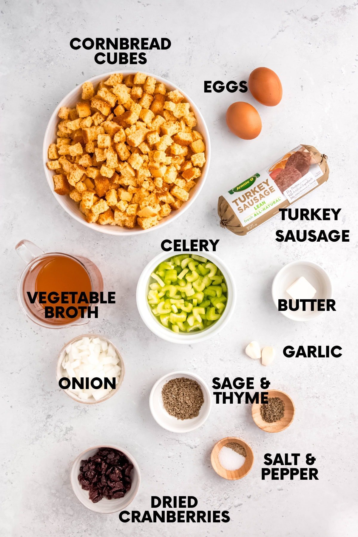 Ingredients for cornbread and sausage dressing: cornbread cubes, eggs, turkey sausage, broth, celery, butter, onion, sage, thyme, salt and pepper, garlic, and dried cranberries.
