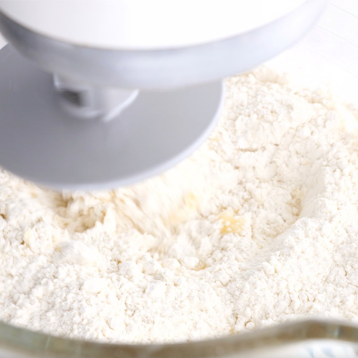A stand mixer fitted with a dough hook mixes dough for yeast rolls.