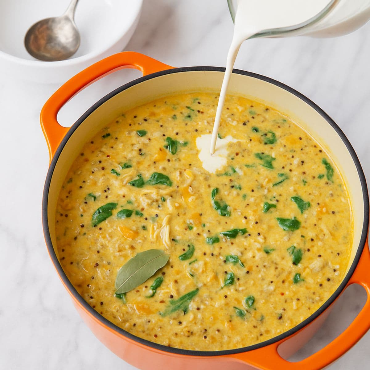 Half and half pours into a pot of soup.