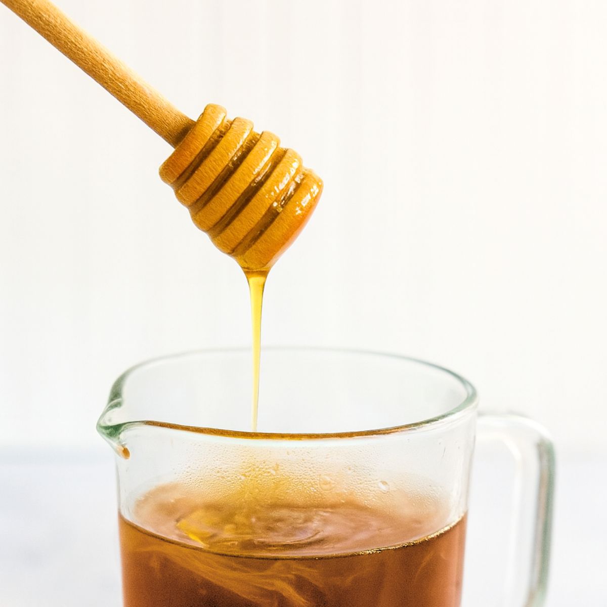 Honey drizzles into a glass pitcher of punch.
