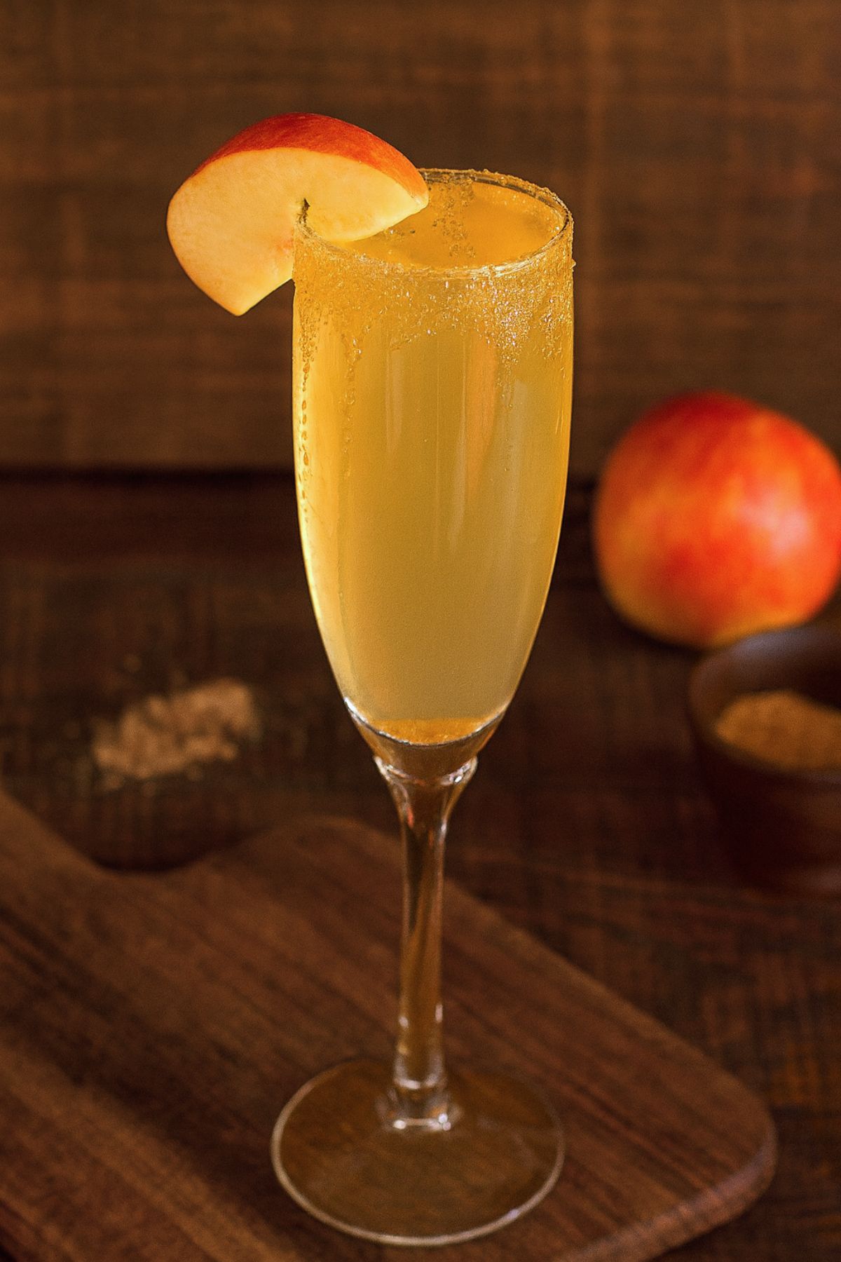 Apple cider mimosa garnished with a brown sugar rim and a slice of apple