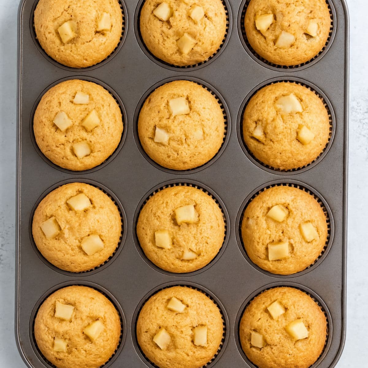 Moist apple cinnamon muffins baked in a muffin tin.