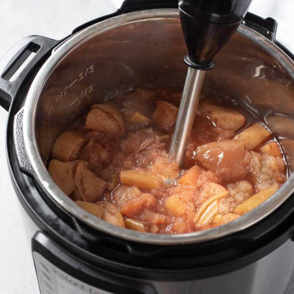 An immersion blender in an Instant Pot of cooked apples