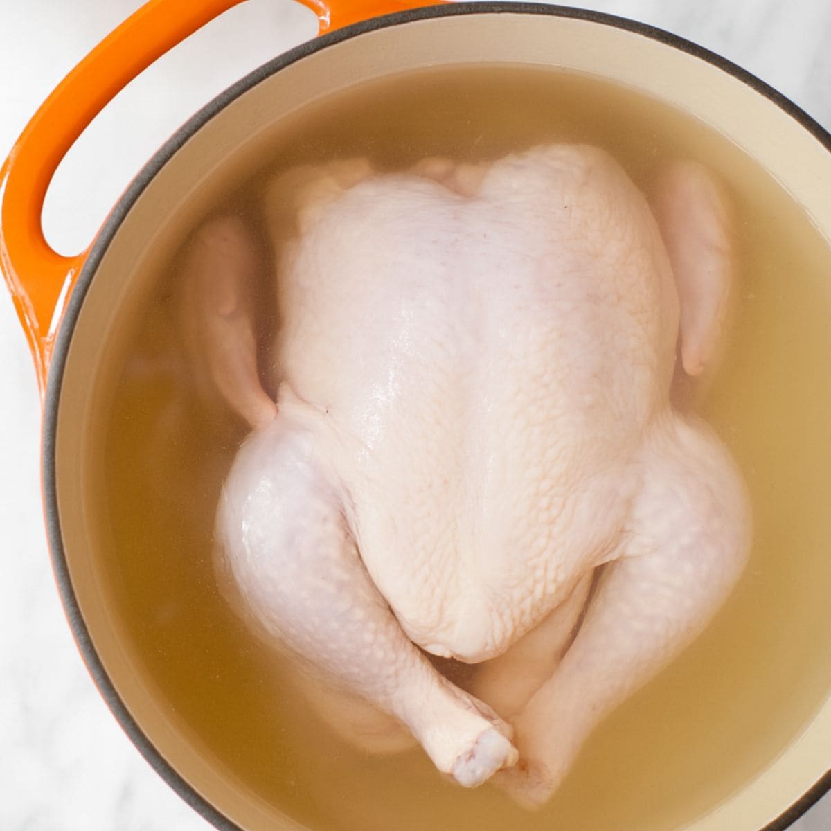 A whole boiled chicken in a pot.