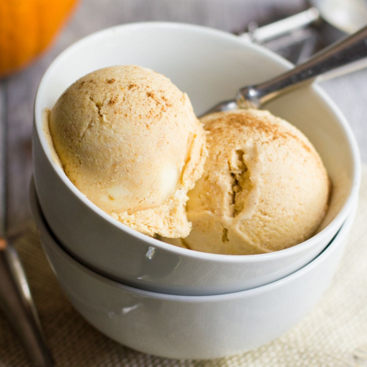 Two scoops of homemade pumpkin ice cream in a white bowl