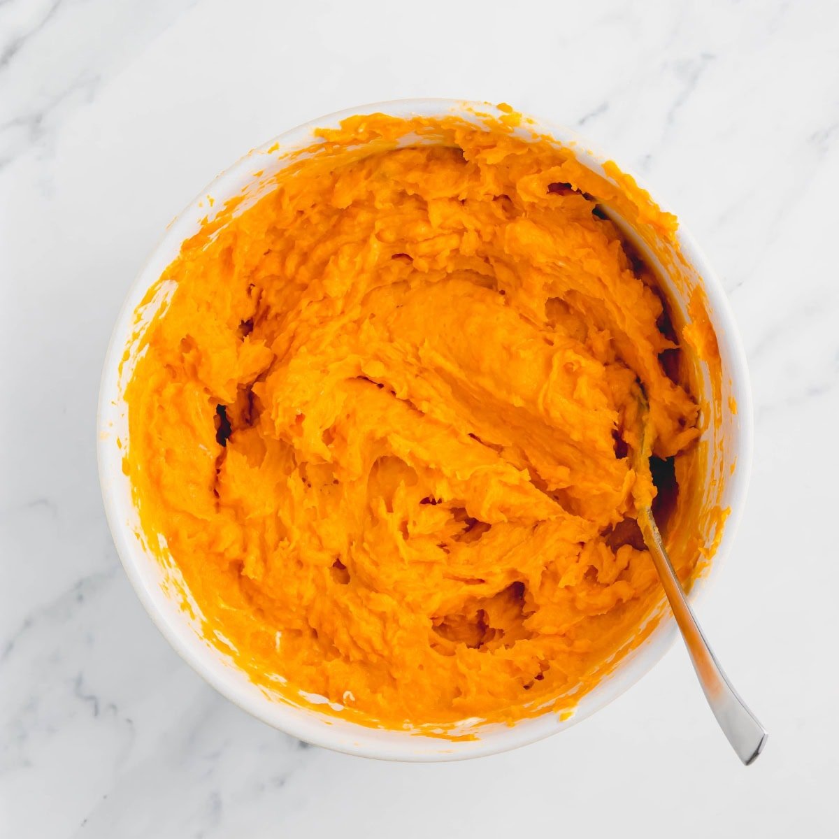 Filling for sweet potato casserole in a white bowl.
