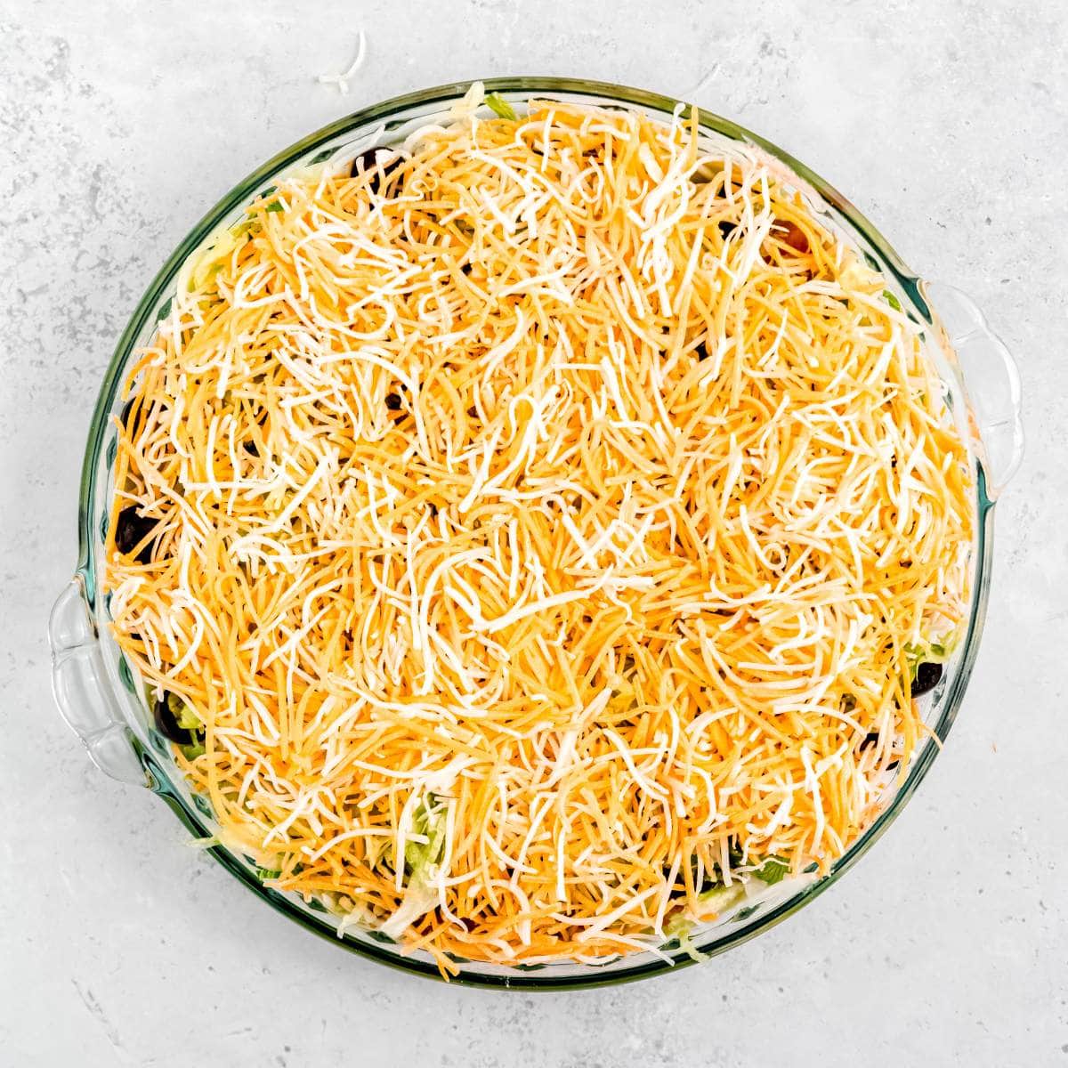 Shredded cheese in an even layer in a pie pan