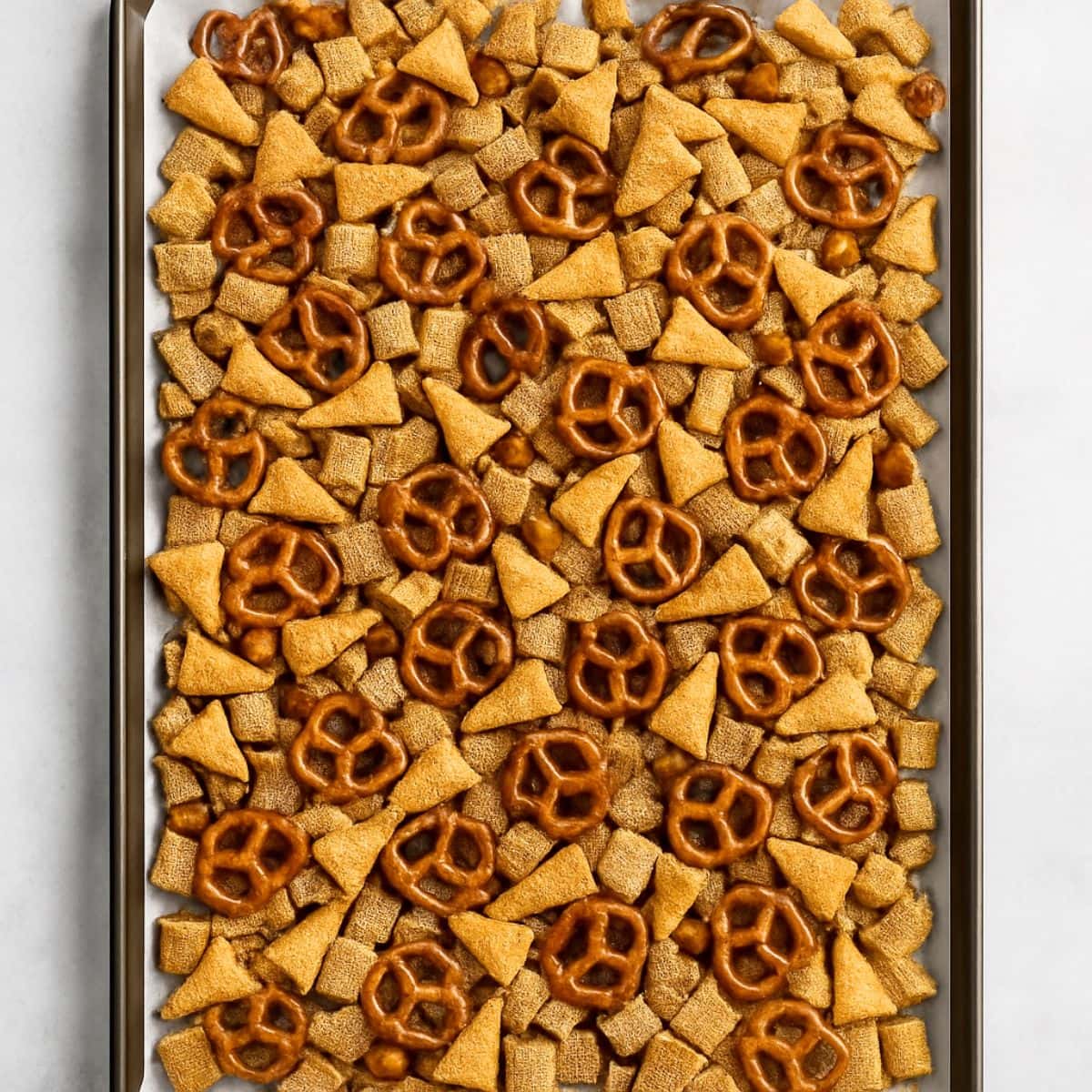 Chex Mix spread out on a baking sheet