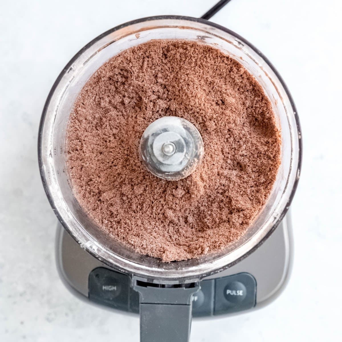 Dry ingredients for a chocolate pie crust in the basin of a food processor.
