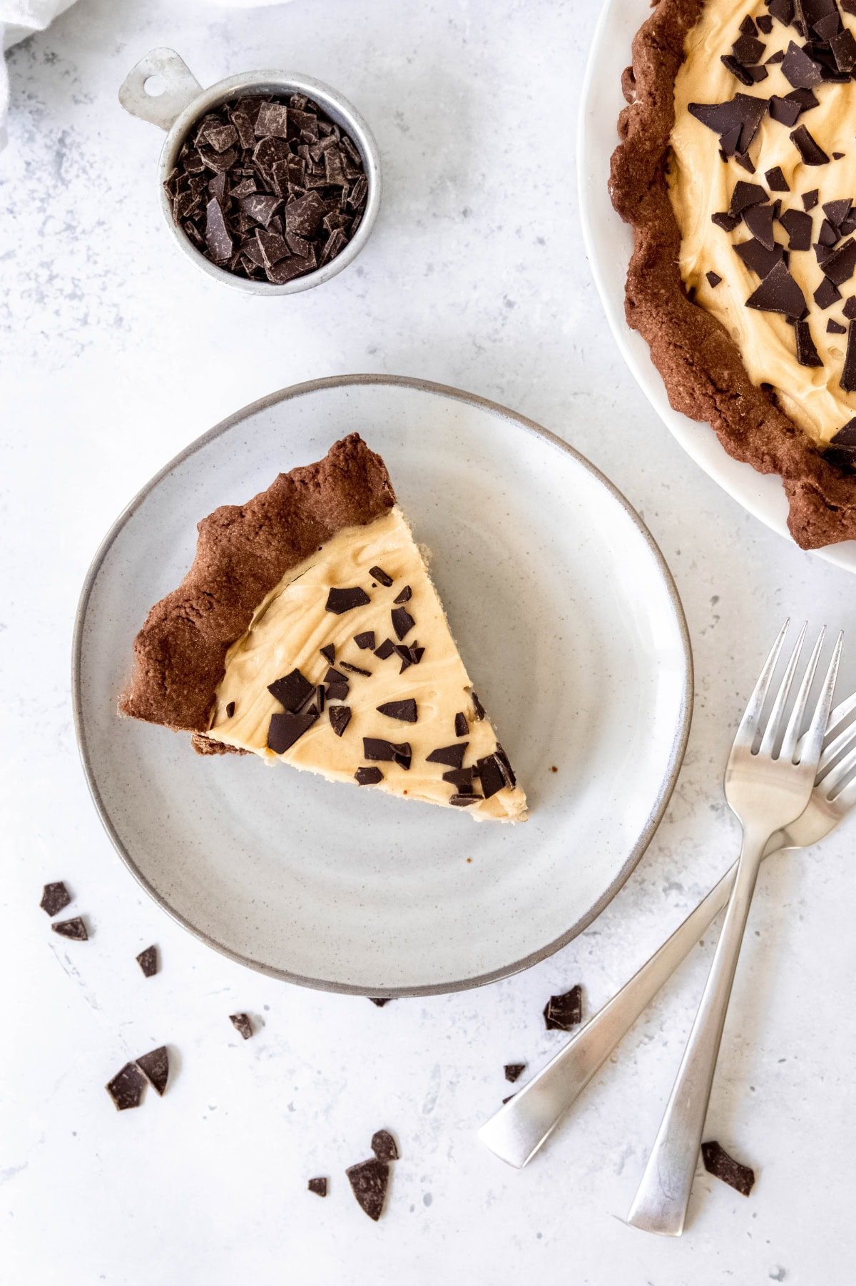 A slice of chocolate peanut butter pie on a plate next to the entire pie.