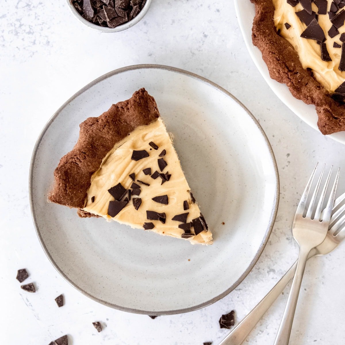 A slice of chocolate peanut butter pie on a plate next to two forks.