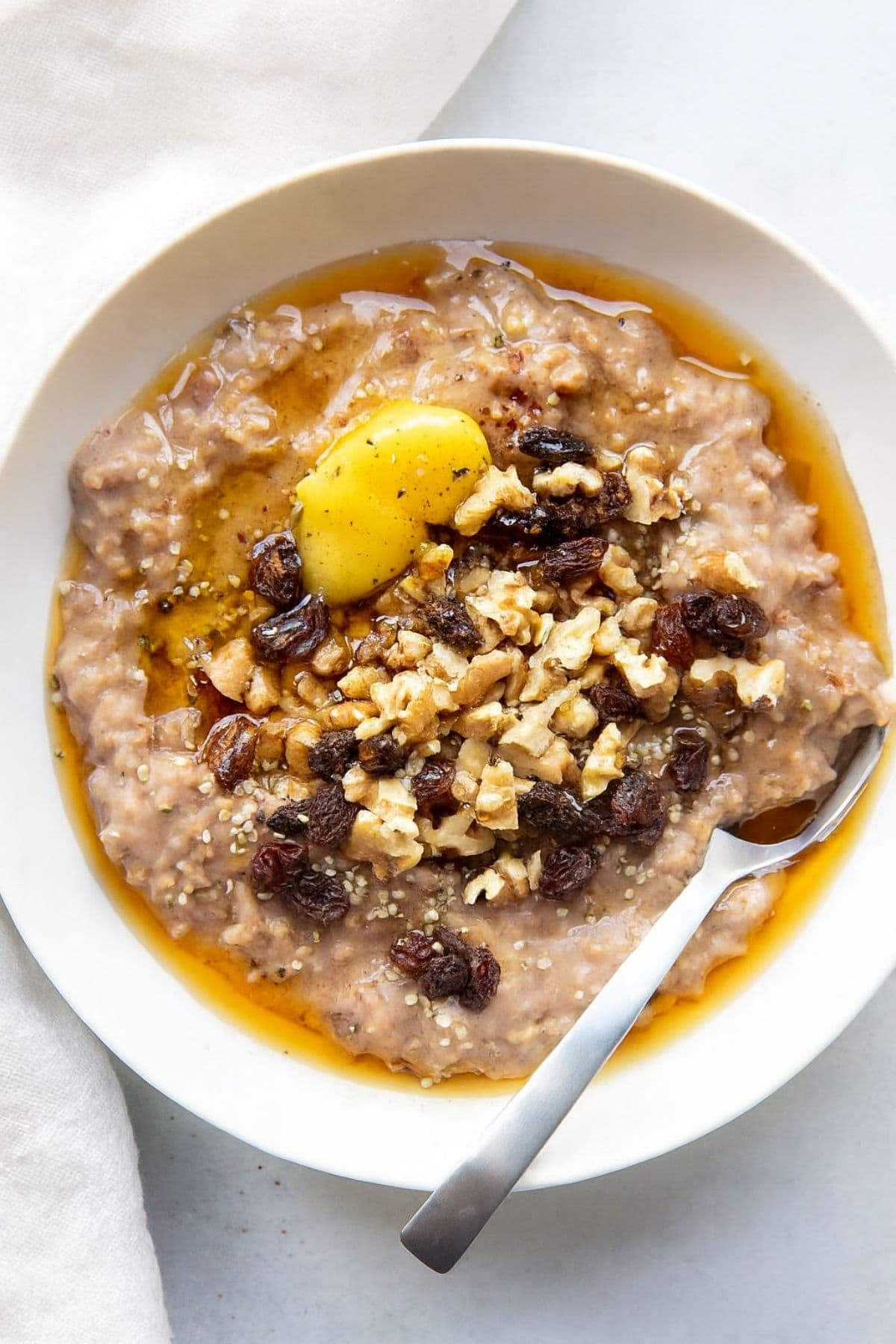 Slow cooker steel cut oats topped with ghee, chopped nuts, and raisins.