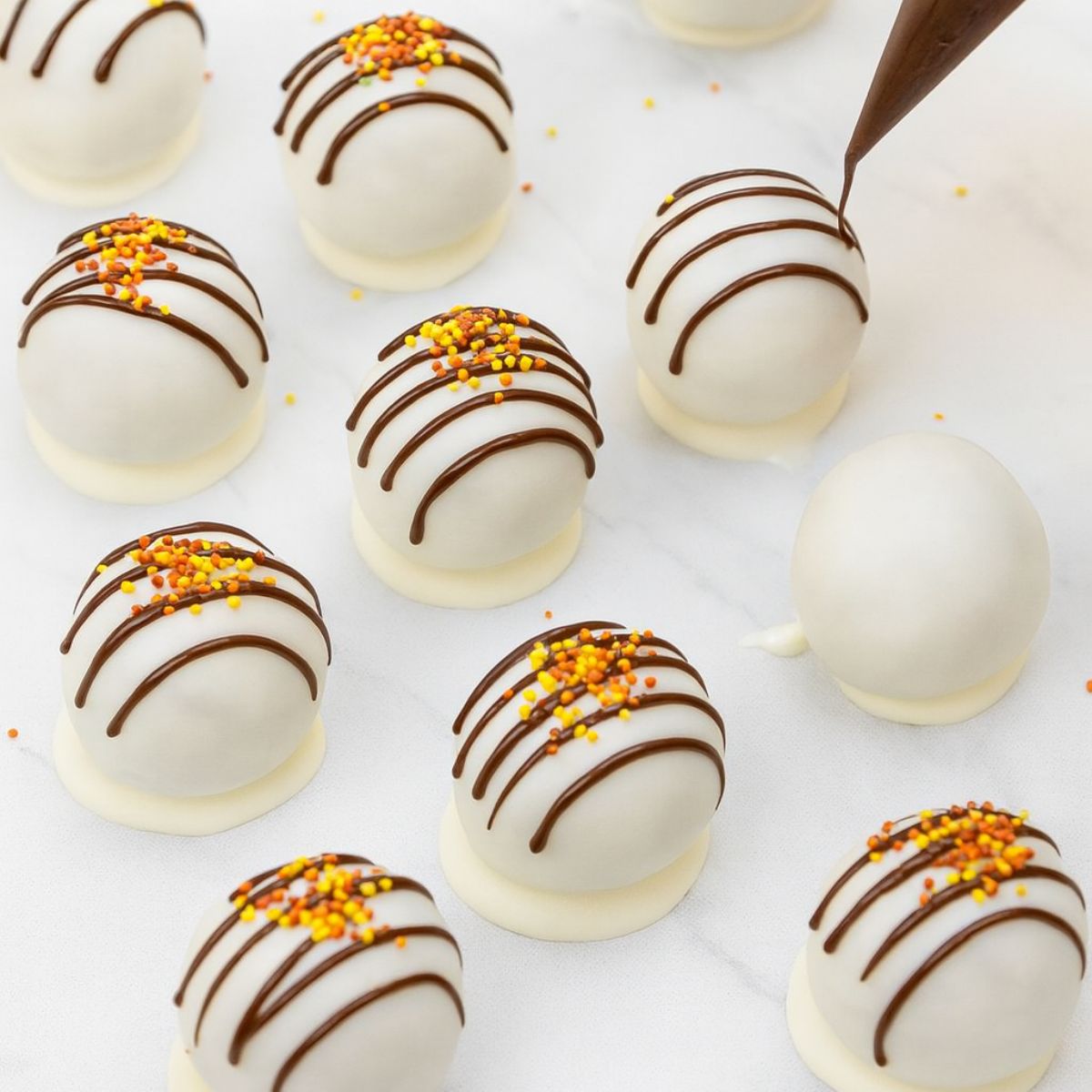 Chocolate drizzle gets piped over cake pops