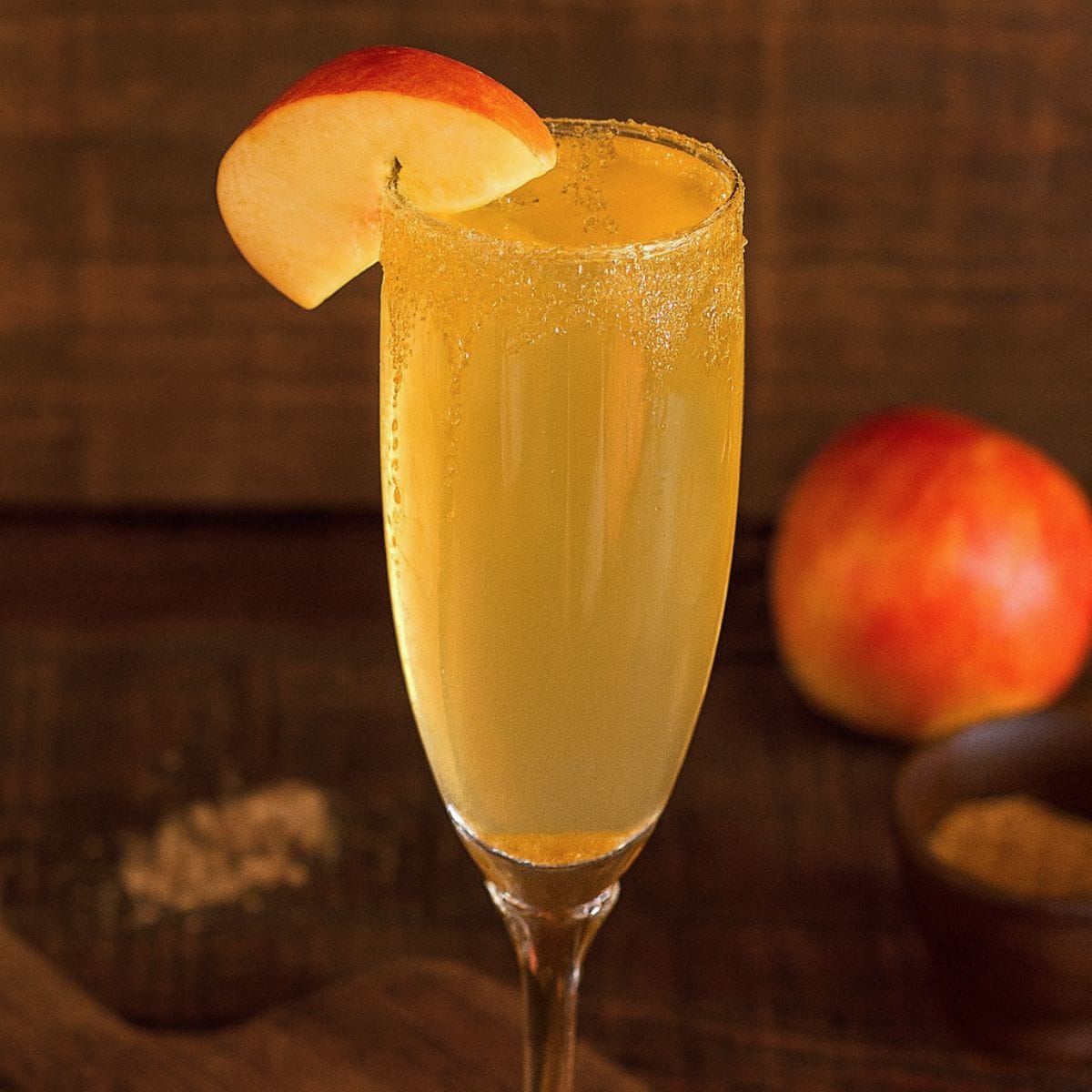Apple cider mimosa with a brown sugar rim and an apple slice garnish