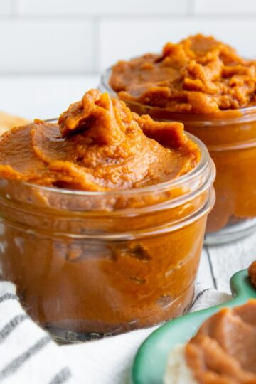 Two jars of pumpkin butter on a striped dishtowel