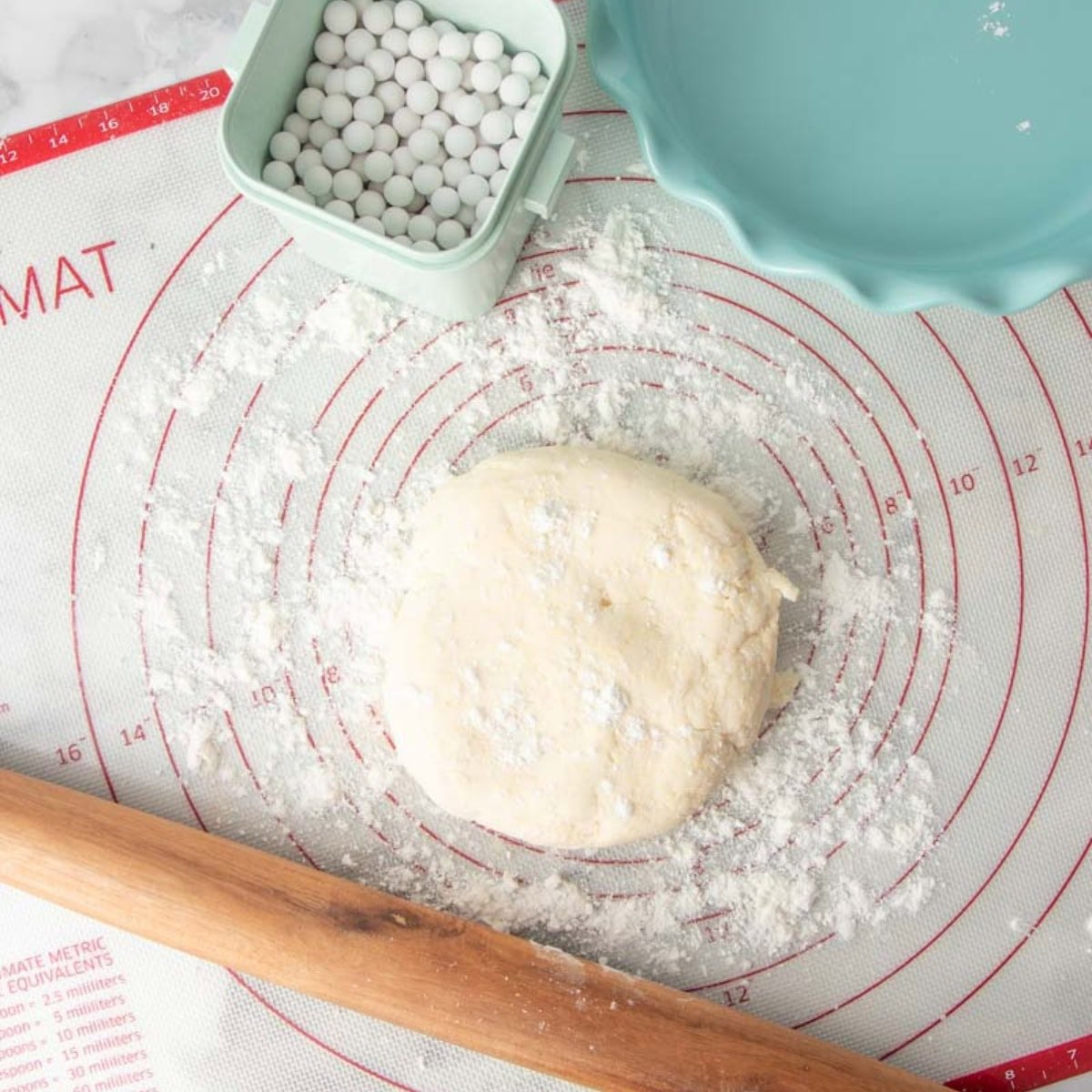 A disc of gluten-free pie dough on a silicone mat.