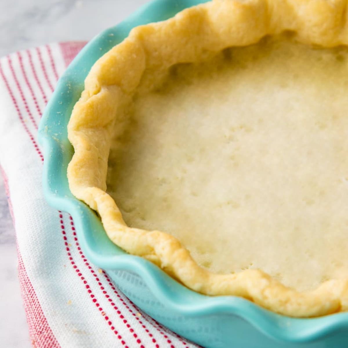 A gluten-free pie crust in a teal pie plate.