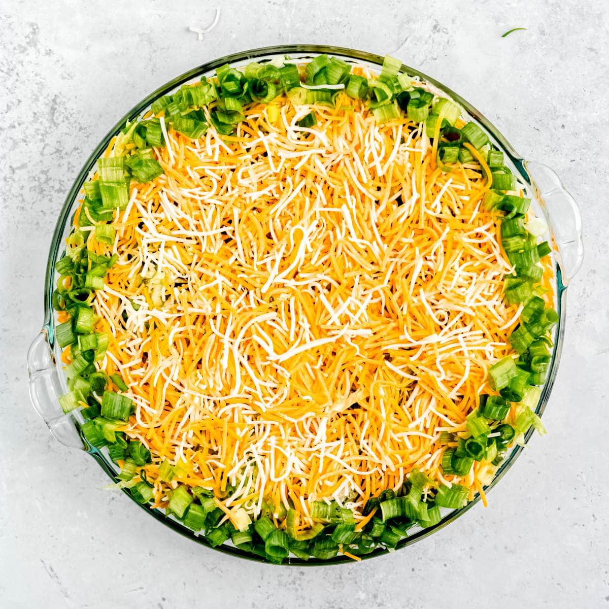 Green onions around the edge of a pan of taco dip