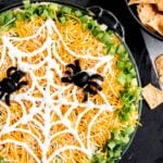 Round pan of Halloween taco dip with a sour cream "spider web" as garnish