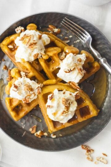 Four pieces of pumpkin waffles on a dark plate