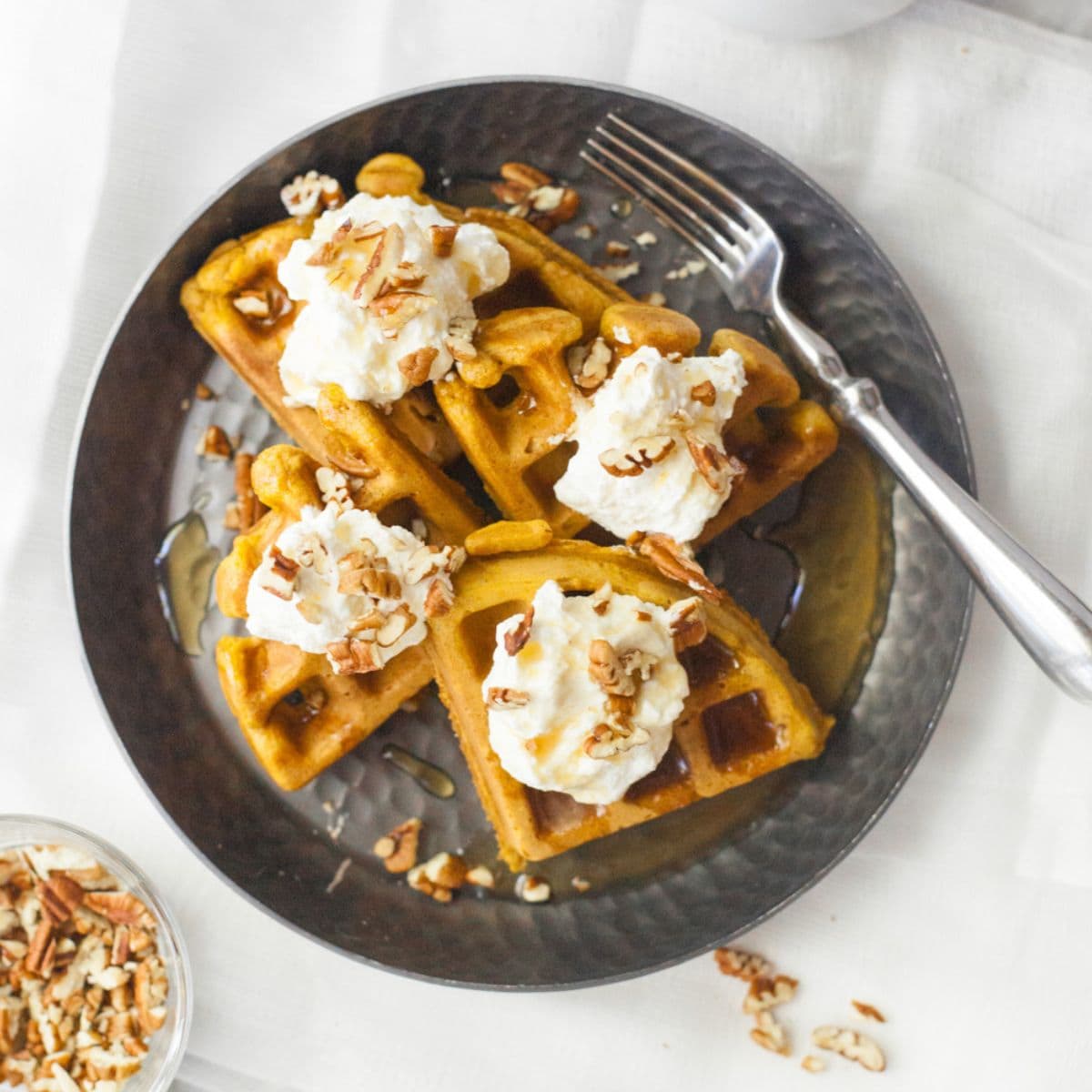 Four pieces of pumpkin waffles on a dark plate