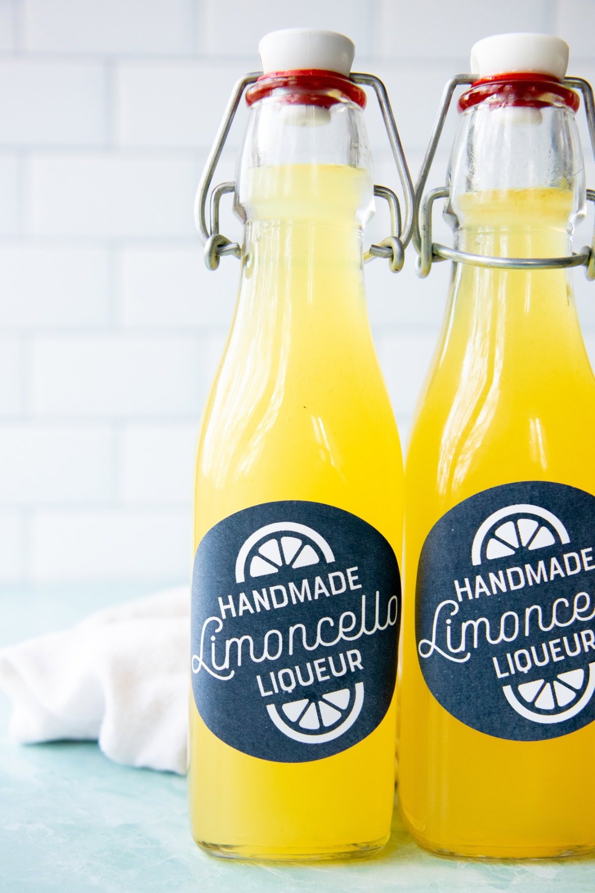 Two swing-top bottles of homemade limoncello stand side-by-side.