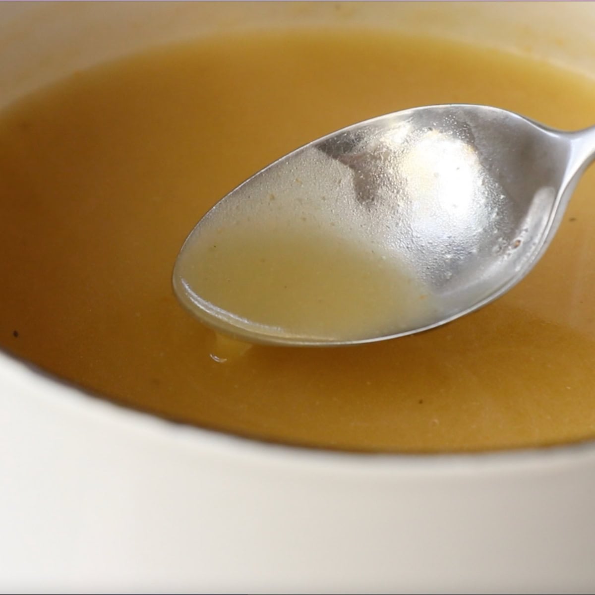 A spoon hovers over a bowl of turkey gravy, showing the appropriate thickness and consistency.