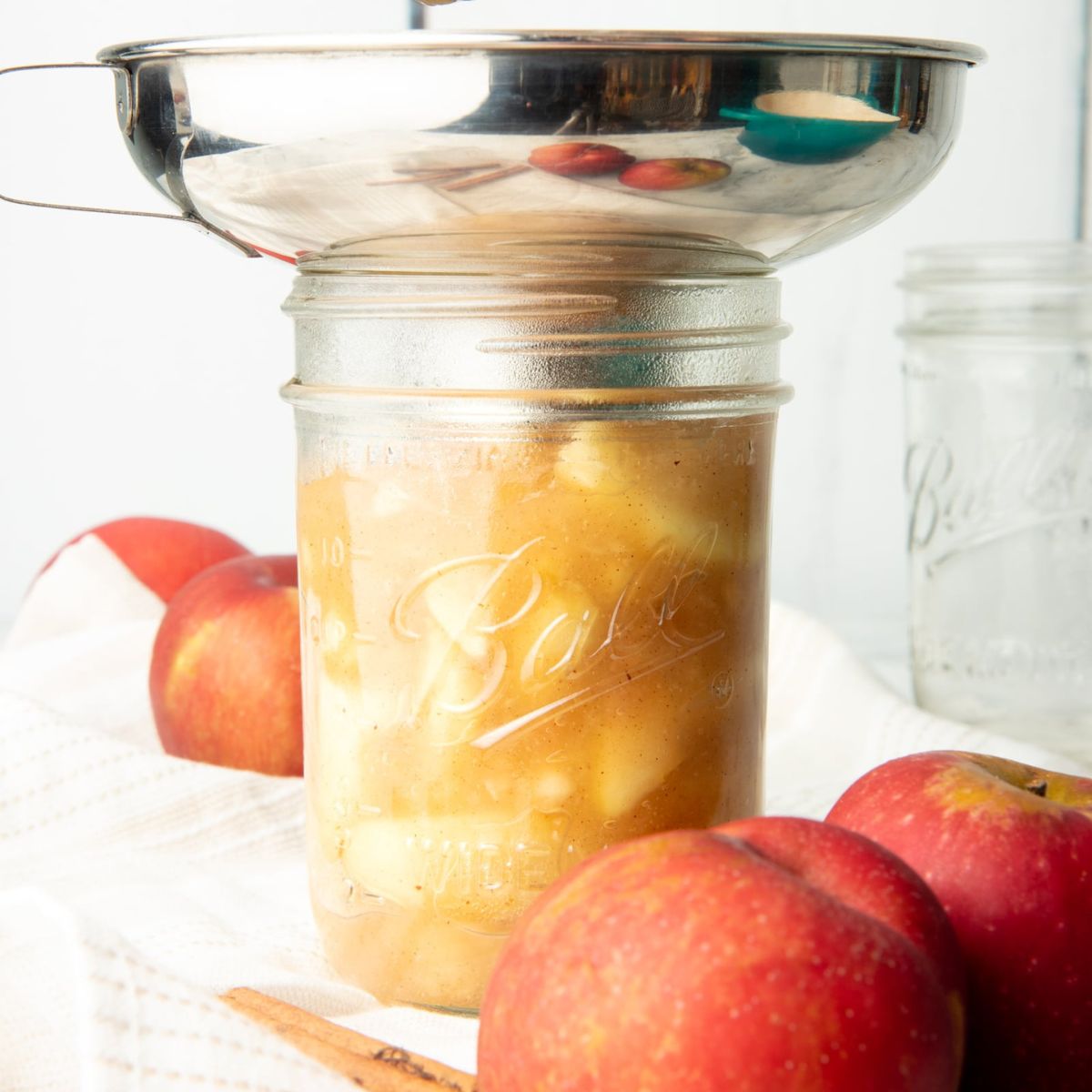 A funnel rests in the mouth of a pint jar to transfer pie filling to the jar.