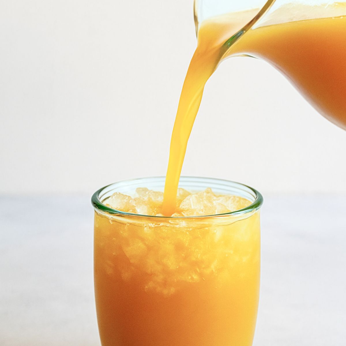 Whiskey punch pours into a glass over crushed ice.