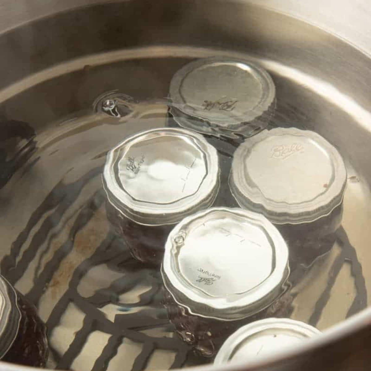 Five jars in a canning pot for canning apple pie filling.