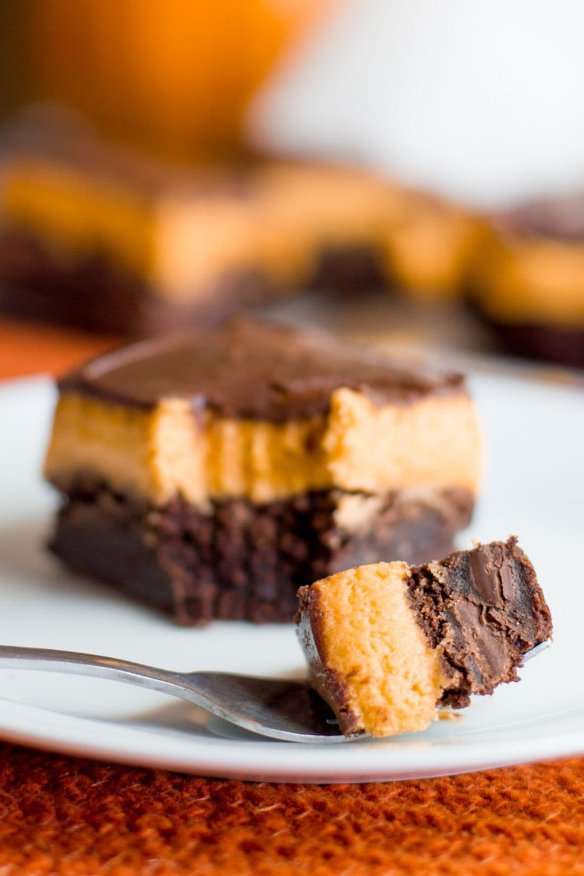 A fork holds a bite of pumpkin brownie in front of the full brownie