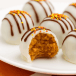 Pumpkin cake pops on a white plate, one with a bite taken out of it.