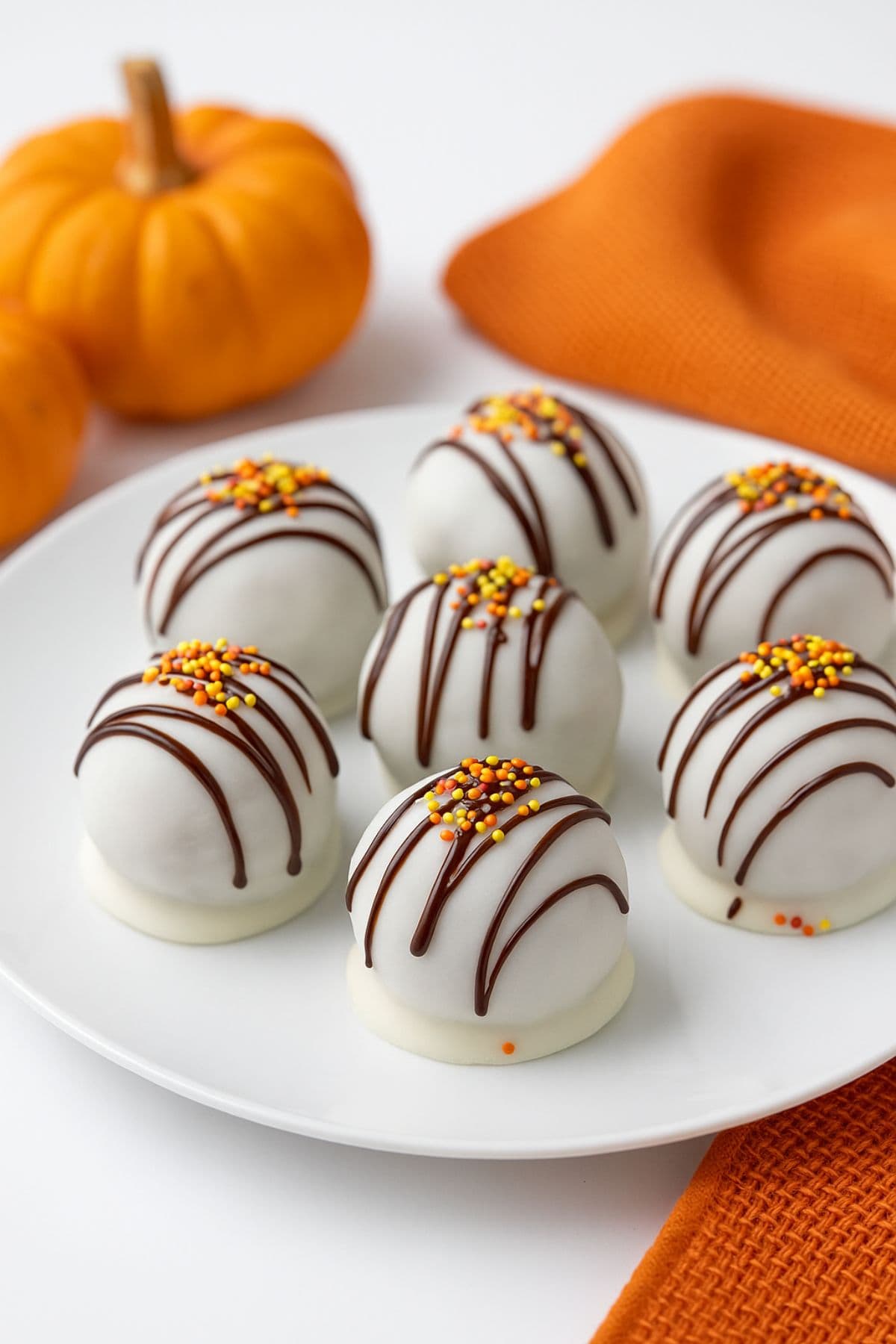 Pumpkin cake balls on a plate near mini pumpkins