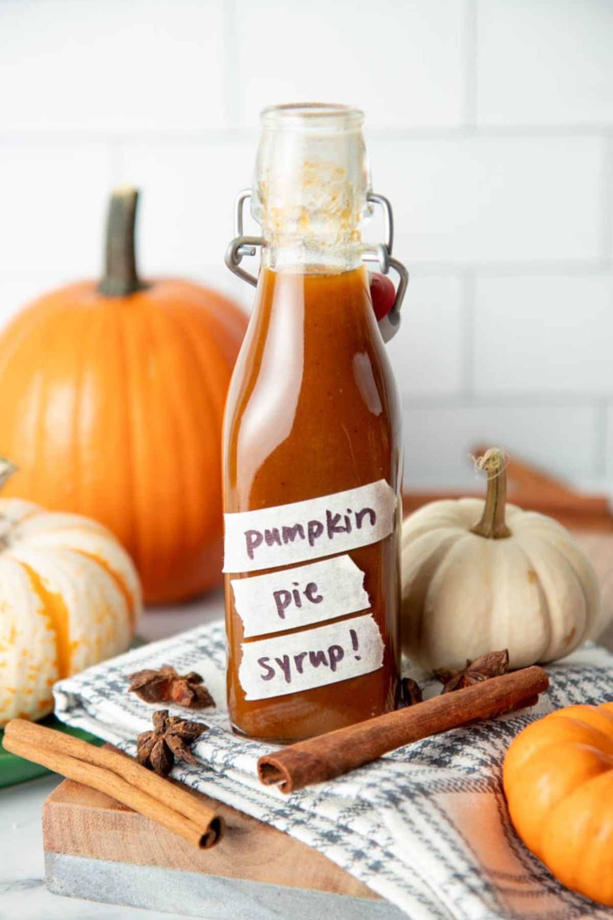 Pumpkin spice syrup recipe in a flip-top bottle surrounded by mini pumpkins