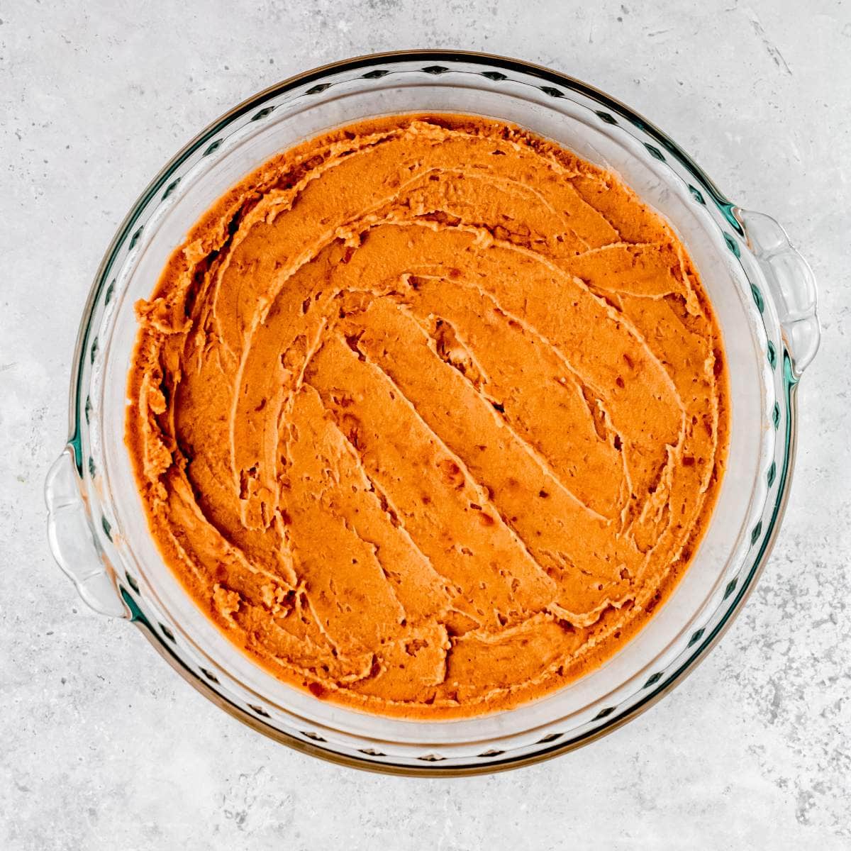 Refried beans in an even layer in a pie plate