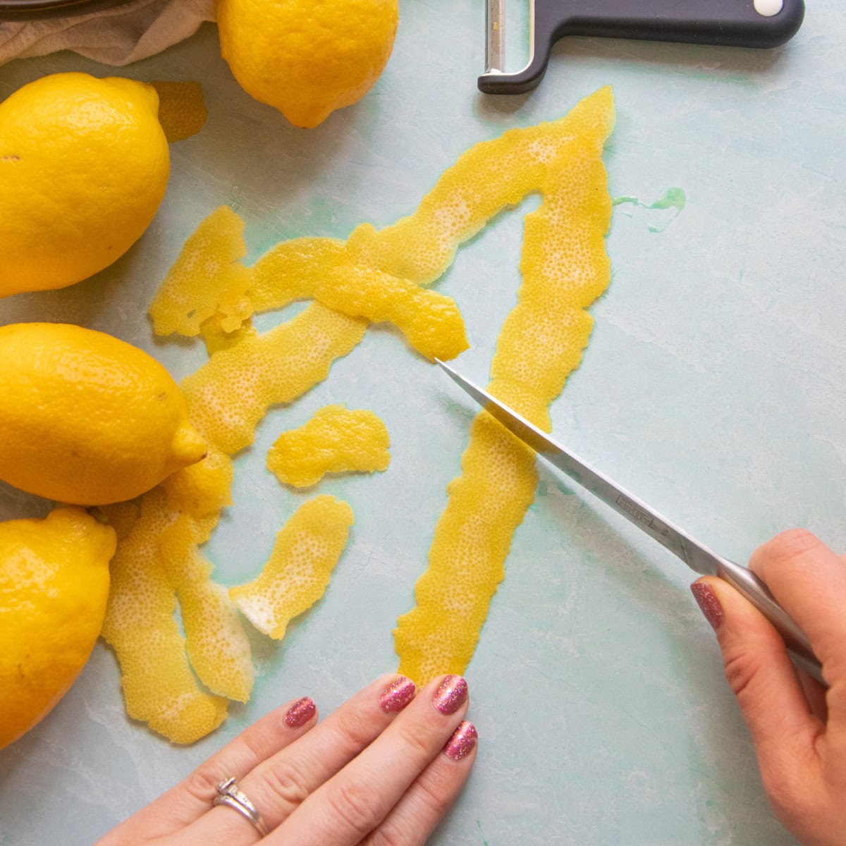 A knife scrapes the pith off of lemon peels.