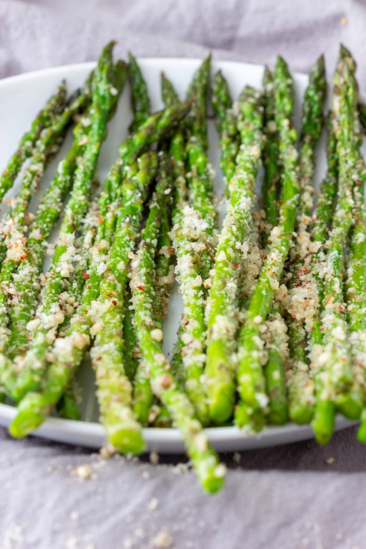 Roasted asparagus and Parmesan on a round white plate.