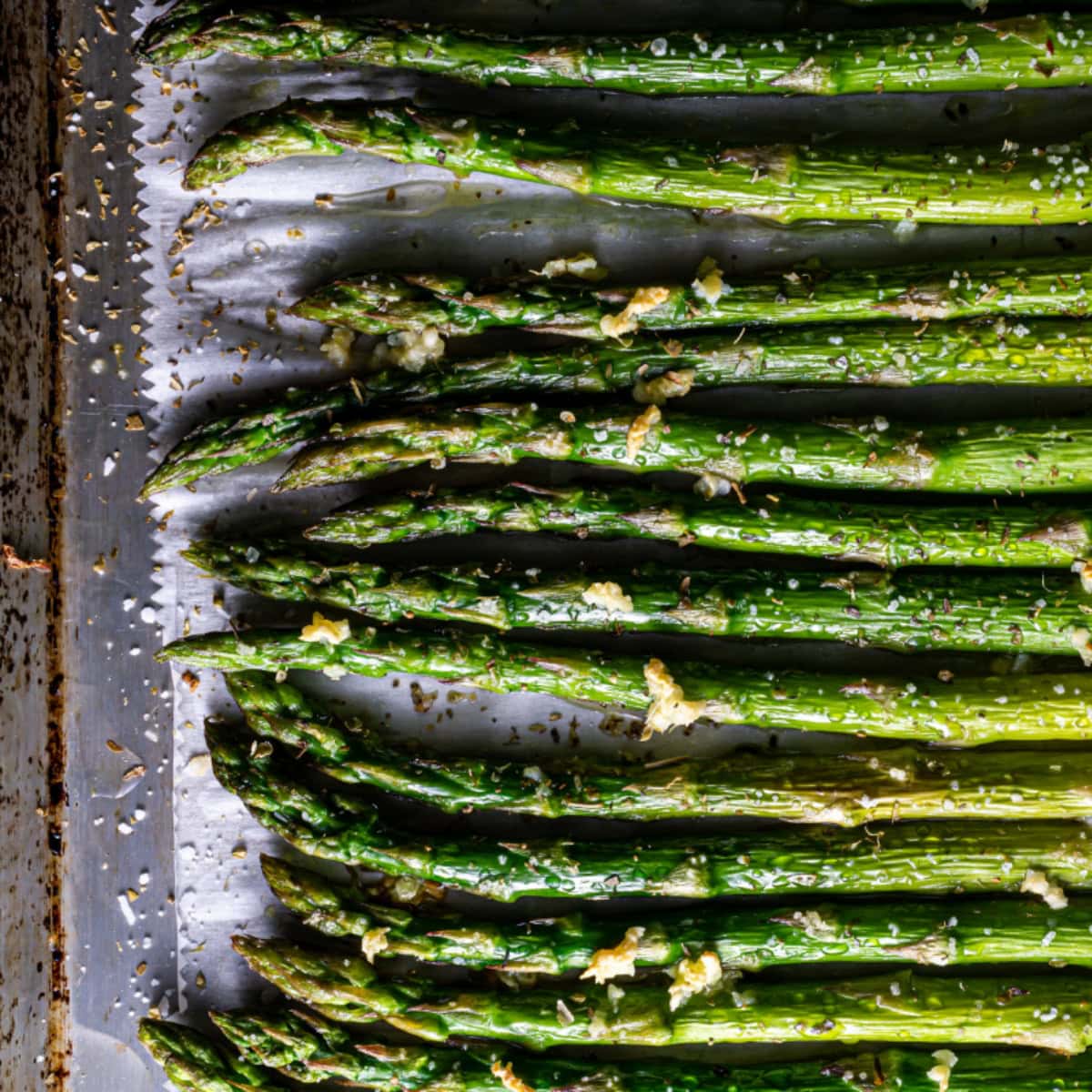 Roasted asparagus spears on a parchment paper-lined baking tray.