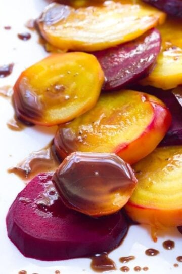 Red and golden beets with balsamic glaze on a white plate.