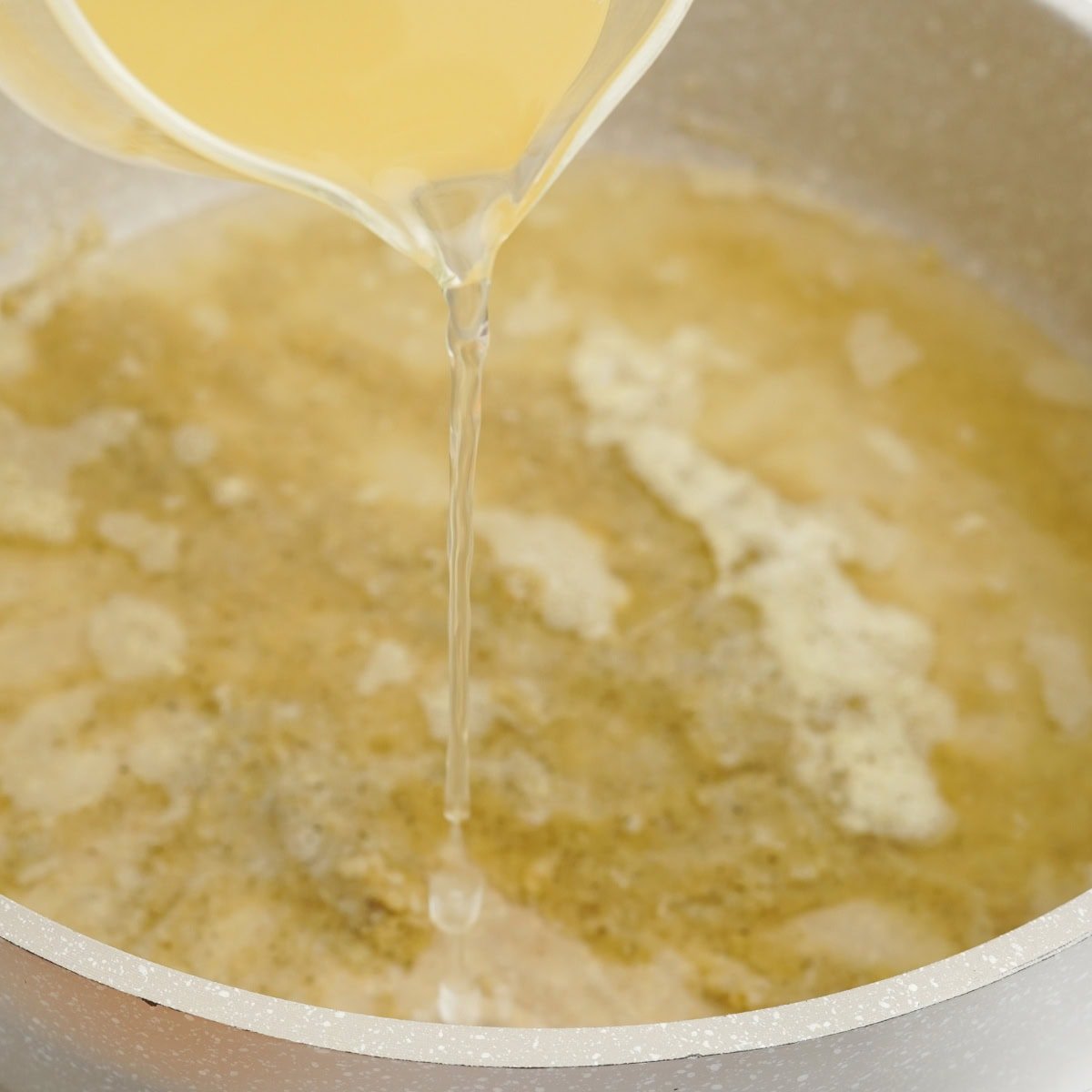 Broth pours into a grey pot.
