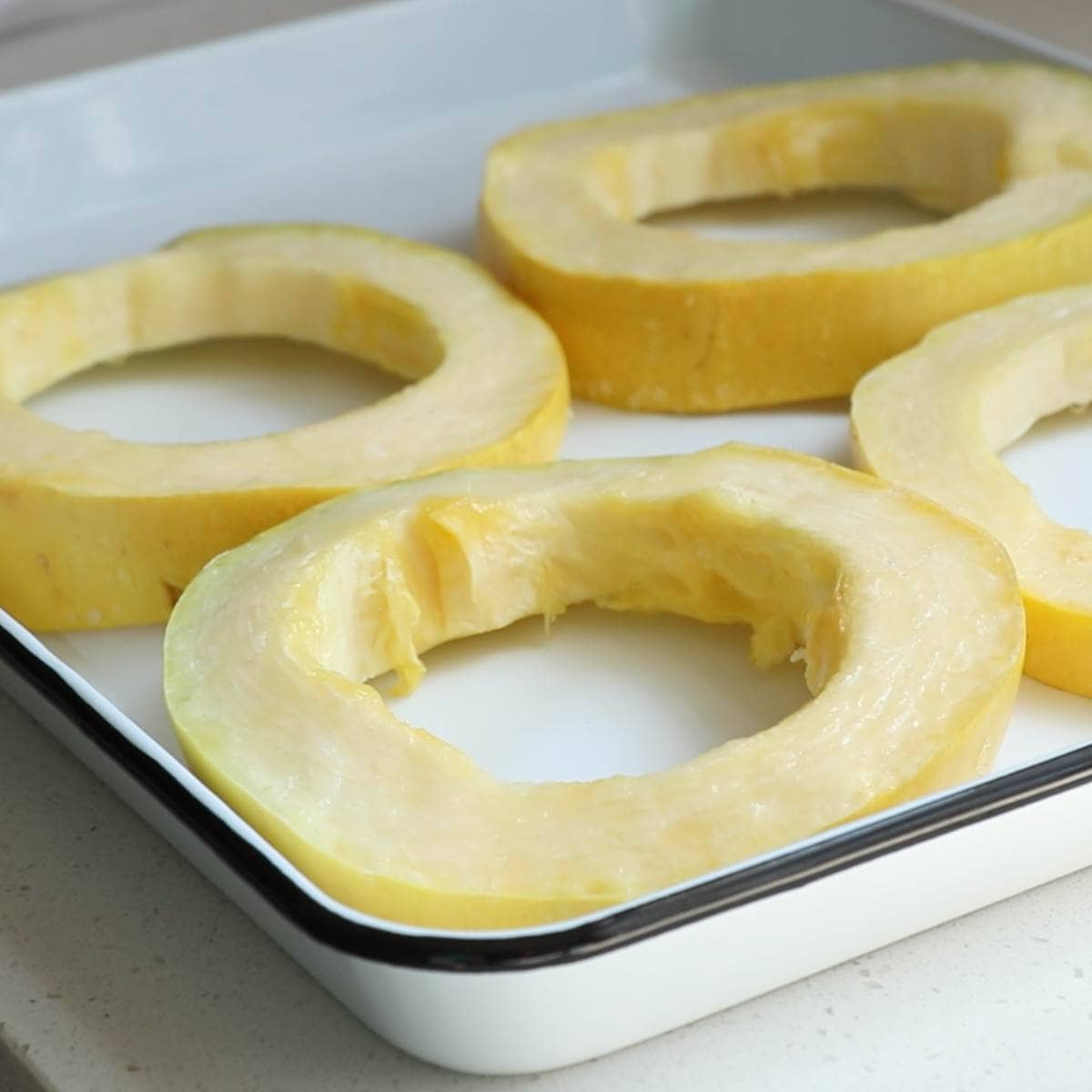 Four rings of spaghetti squash arranged on a baking tray