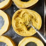 A fork has pulled spaghetti squash noodles out of a ring of roasted squash
