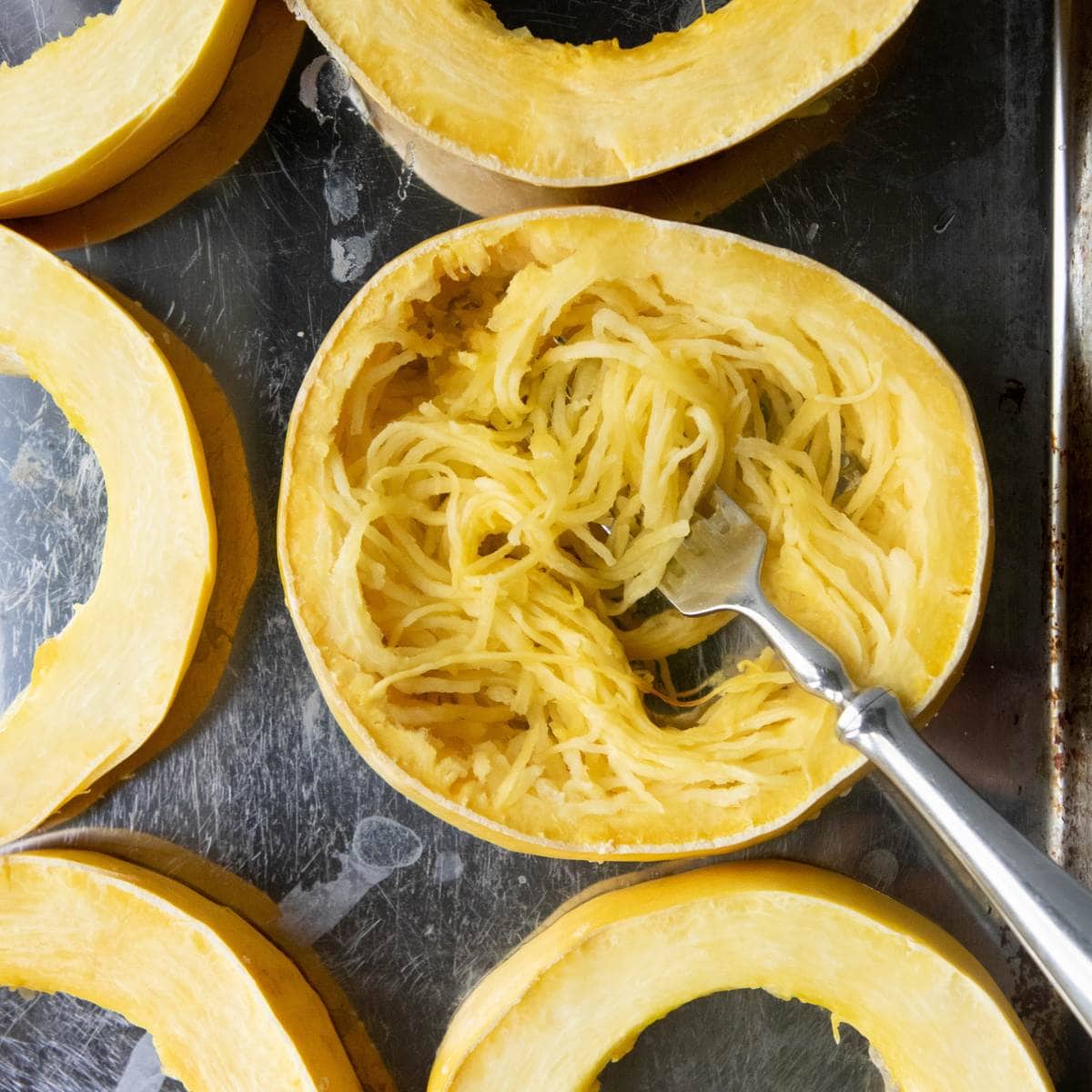 A fork has pulled spaghetti squash noodles out of a ring of roasted squash