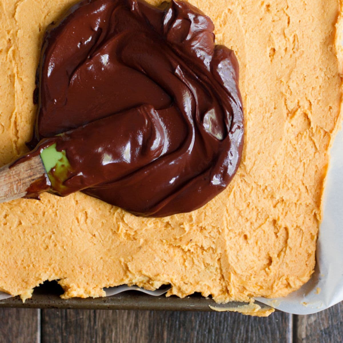 Offset spatula spreads chocolate on top of pumpkin filling