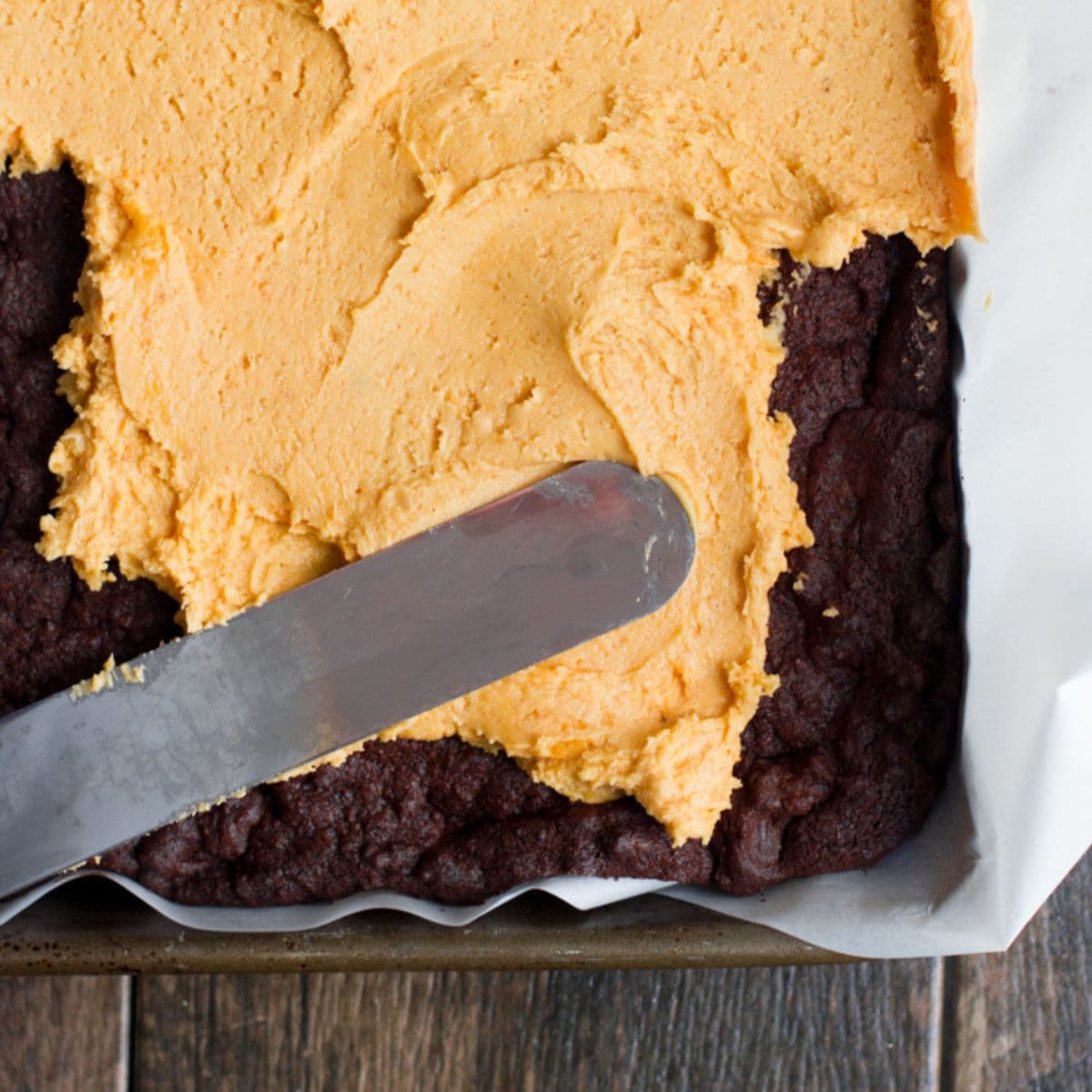 Offset spatula spreads pumpkin filling on top of brownies