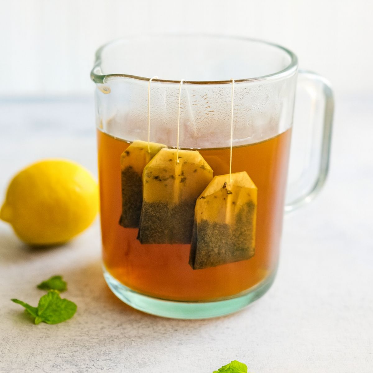 Iced tea steeps in a clear glass pitcher.