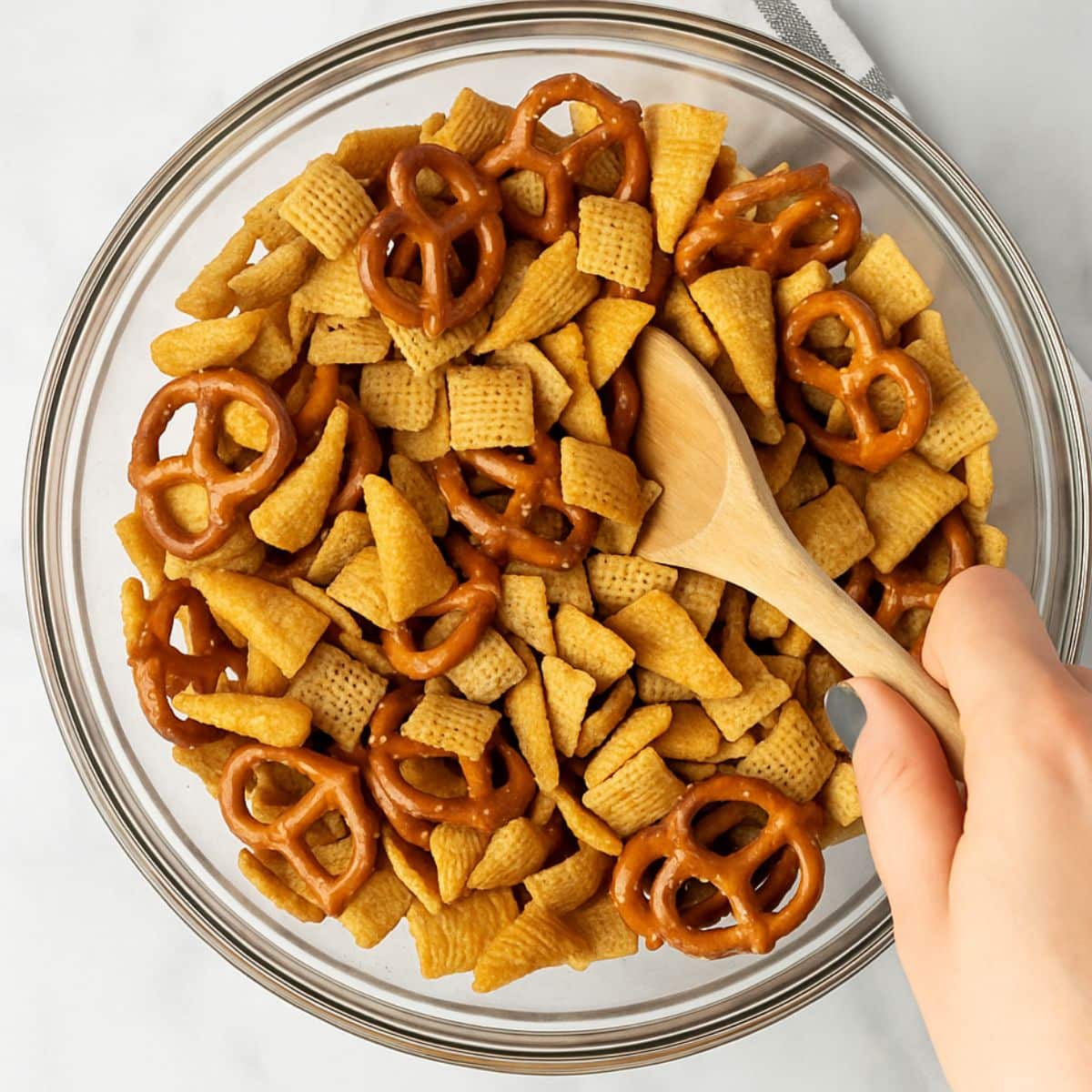 Wooden spoon stirs cereal with pretzels and corn chips