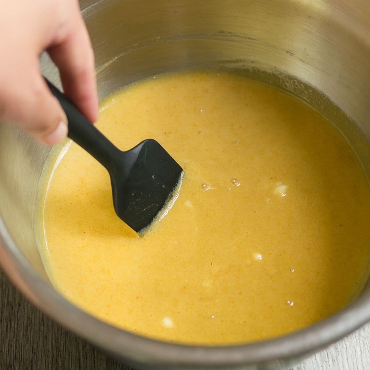 Rubber spatula stirs pumpkin and sweetened condensed milk together